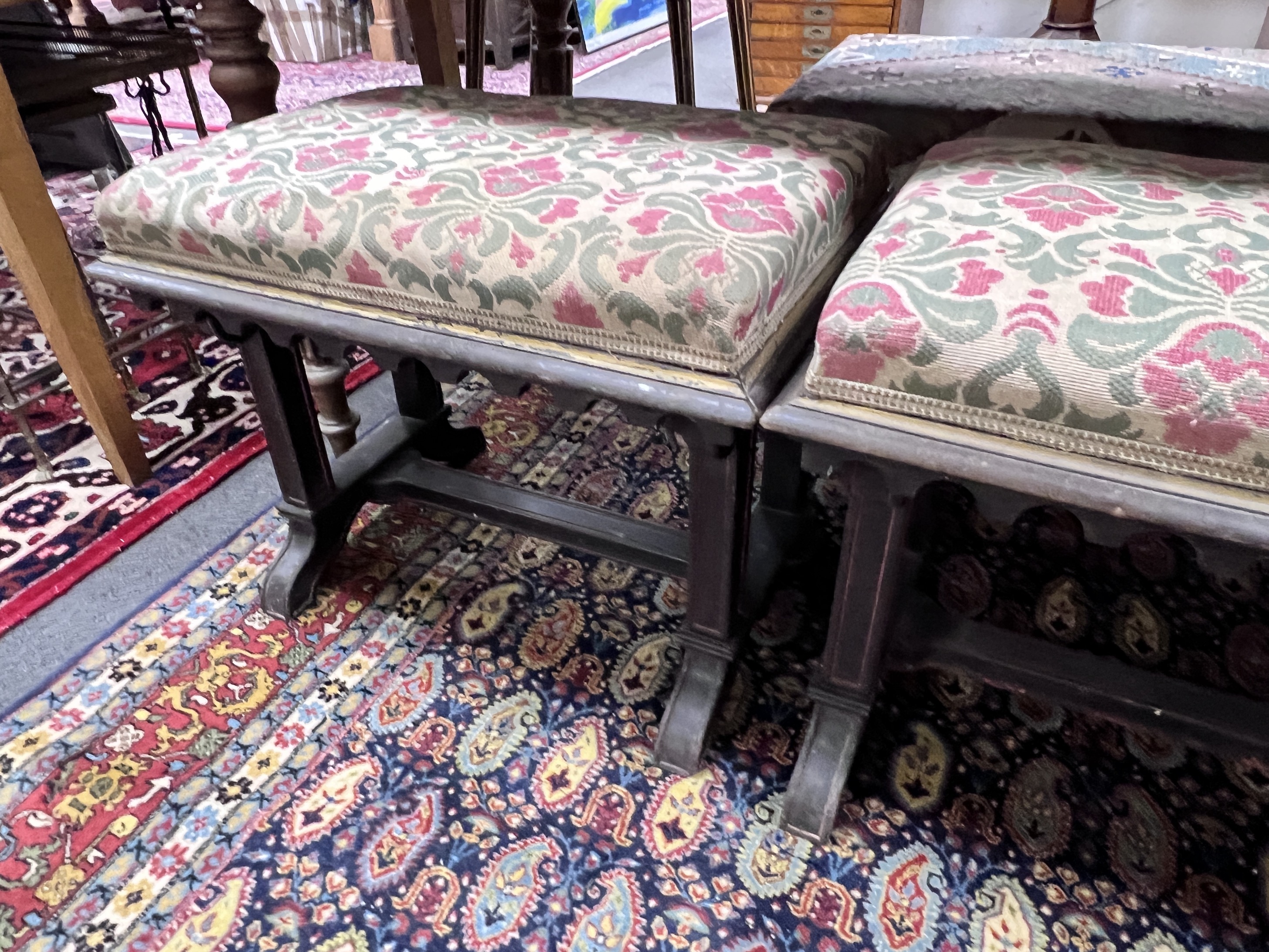 A pair of Victorian upholstered and ebonised stools of neo Gothic design, width 58cm, height 47cm